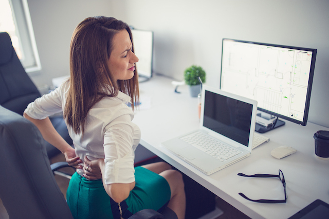 This is a picture of a woman sitting in a chair with low back pain.  Chiropractic care for low back is effective for providing fast and long lasting relief.