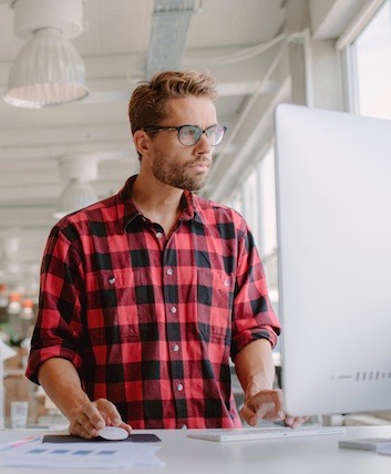 This is a picture of a man using a standing desk.  You can use a standing desk to help improve your posture.