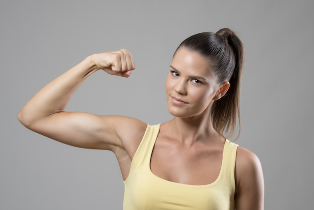 This is a picture of a woman flexing  her bicep muscle. It represents how you can get stronger with chiropractic care.