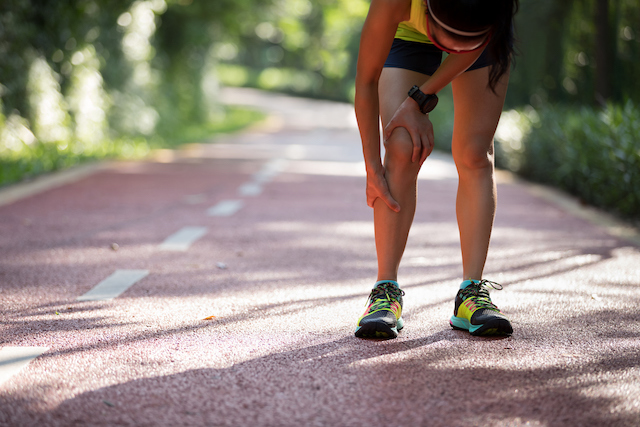 Picture of a runner grasping her leg because of pinched nerves causing weak legs.
