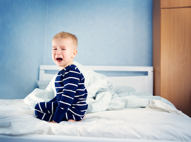 This is a picture of a young child crying in bed because of growing pains.