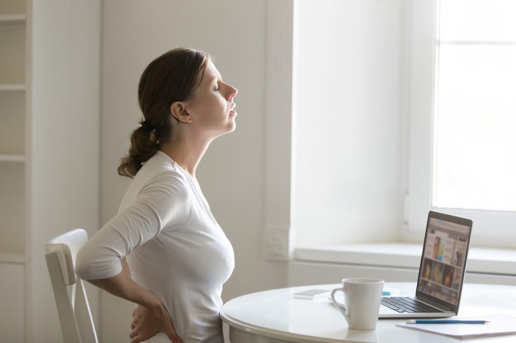 This is a picture of a woman having back pain when sitting at a desk.