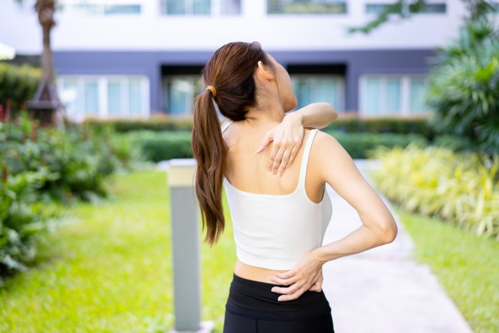 Person experiencing mid back pain when taking a deep breath which depicts the title of the post 'Why Does My Back Hurt When I Take a Deep Breath?'